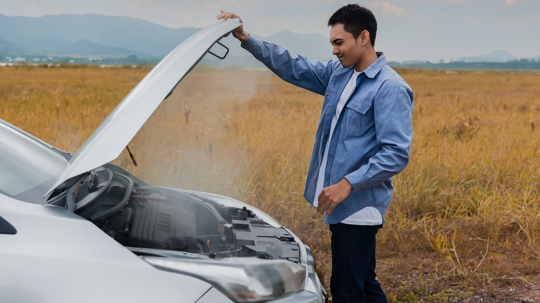 A man in front of an overheating car