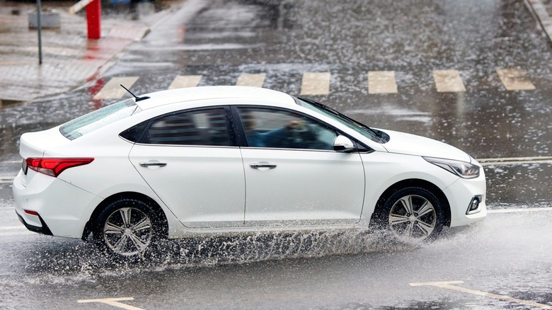 White car driving on a wet city road