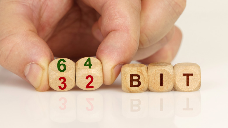 Close-up of a man's hands holding cubes with the inscriptions 64-bit and 32-bit