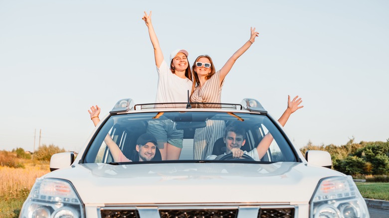 People standing through car sunroof