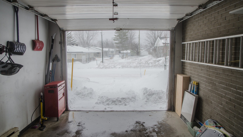 Shot from inside a garage looking out to a snowy driveway