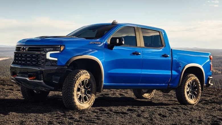 A blue Chevrolet Silverado ZR2 parked off-road with hills and a partly cloudy sky in the background.