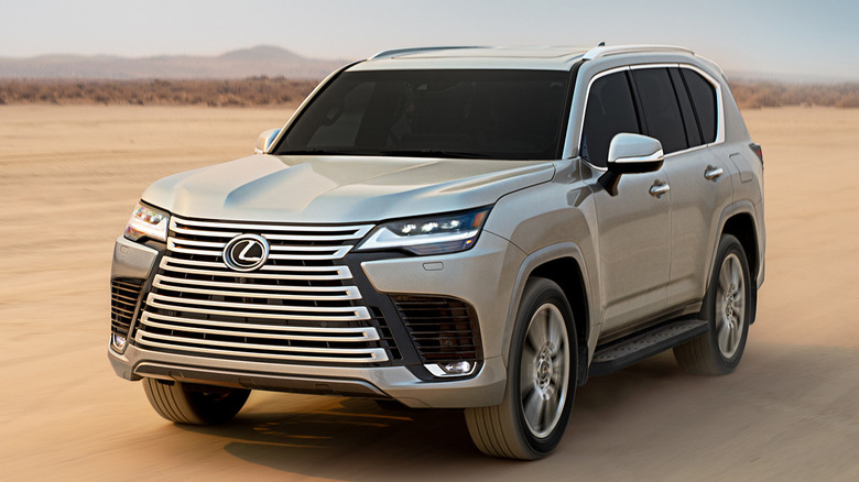 Front 3/4 view of silver Lexus LX600 driving on sand