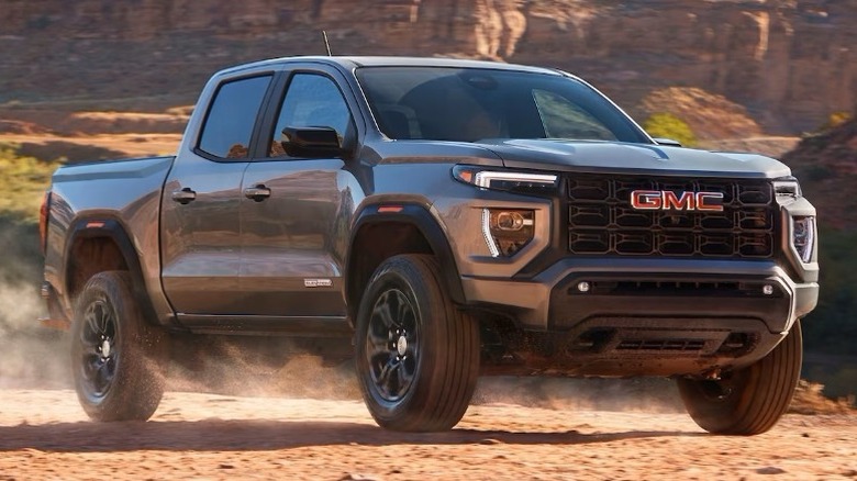 Front 3/4 shot of a GMC Canyon on a dirt road with a rocky landscape in the background