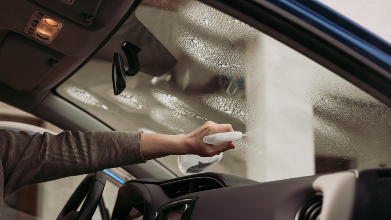 driver cleaning inside of windshield