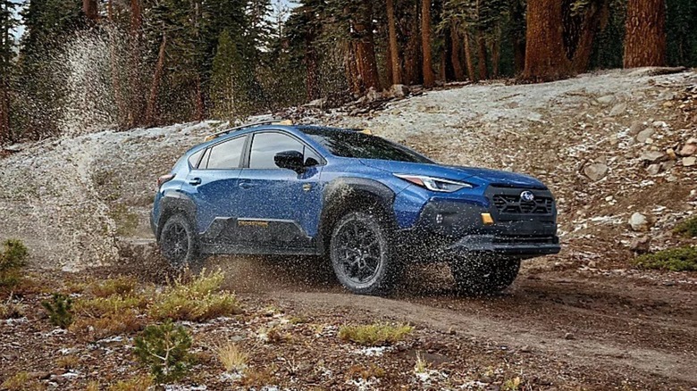 2024 Subaru Crosstrek splashing through puddles on a mountain road.