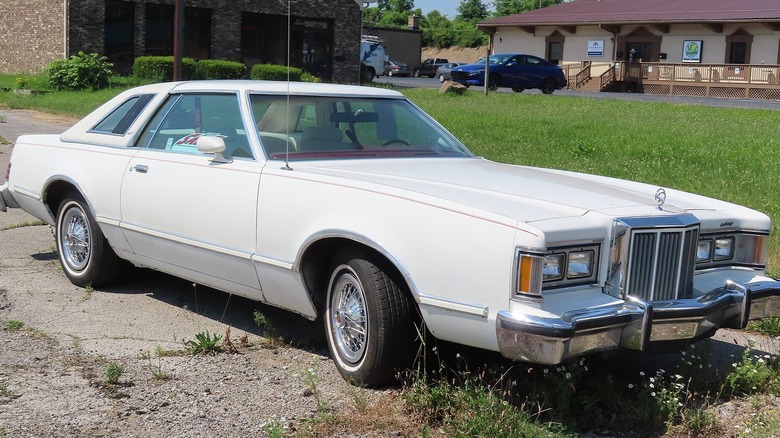 White 1979 Mercury Cougar parked in front of grass yard and houses