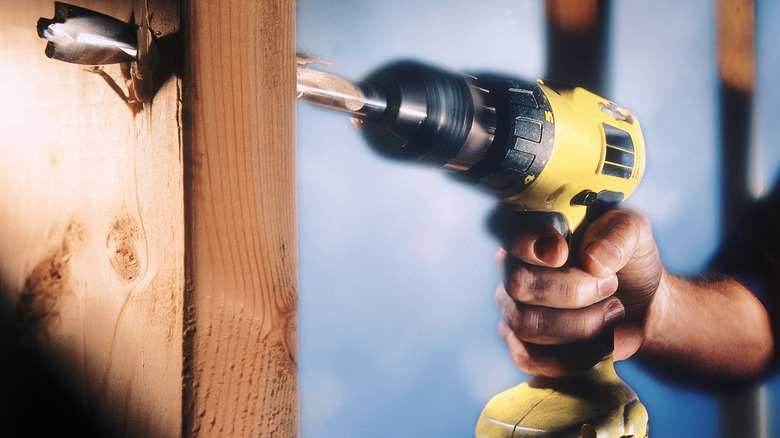 Man Using Power Drill To Bore Into Wood