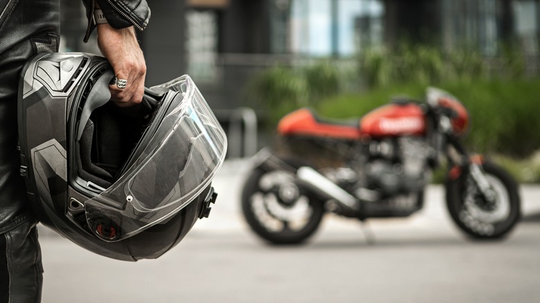 hand holding helmet by motorcycle