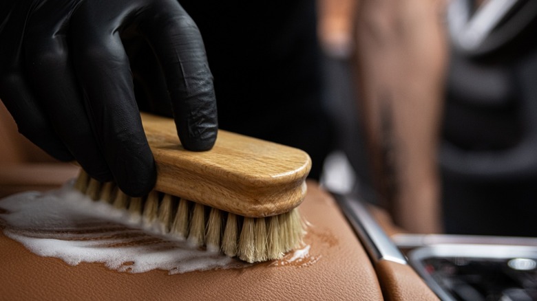 person hand scrubbing leather seat