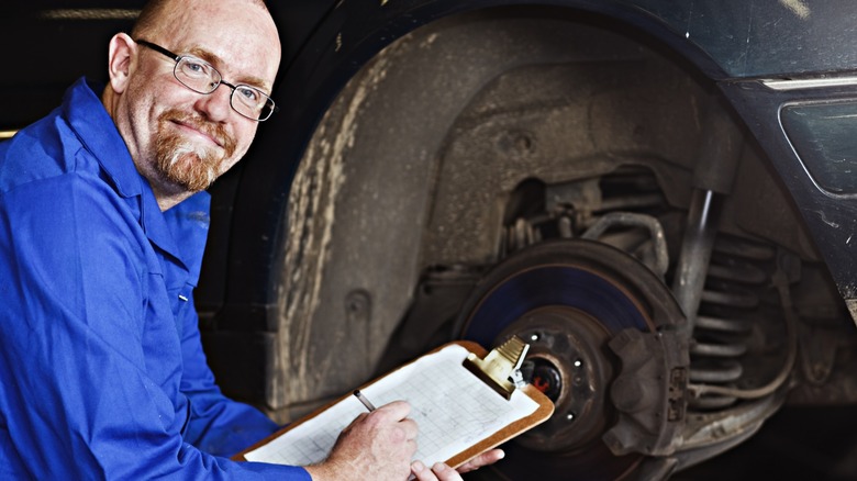 Mechanic crouched in front of a car