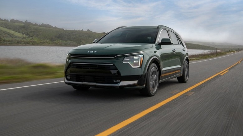 CityScape green Kia Niro driving down a road next to a body of water