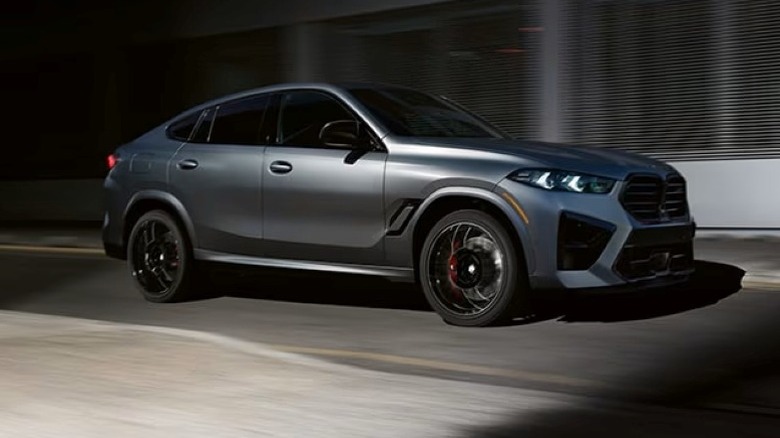 2025 BMW X6 M Competition driving down a city street at night