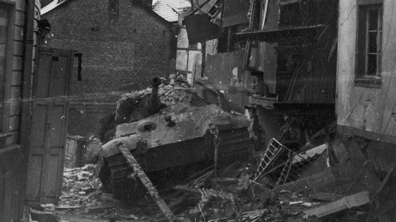 A Tiger II tank disabled in a rubble-filled street.