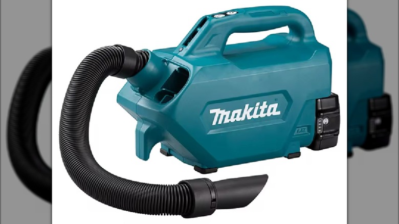 A Makita hand vacuum with the hose unraveled.