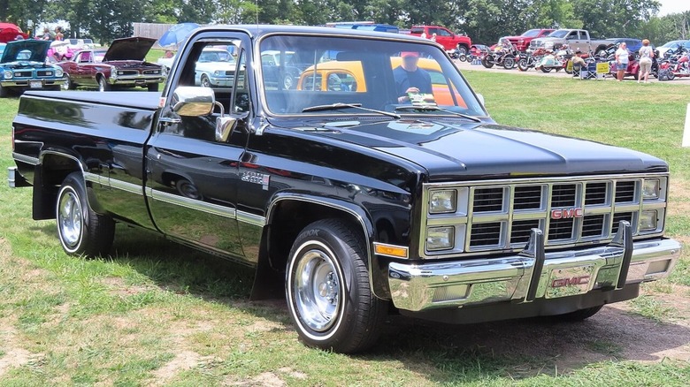 A black 1981 GMC Sierra Classic square body on display at an outdoor car show