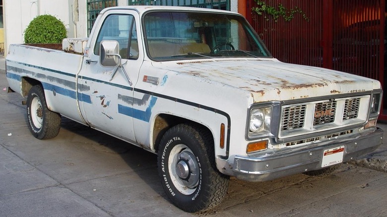 A white 1973 GMC square-body pickup with blue and gray pinstripes