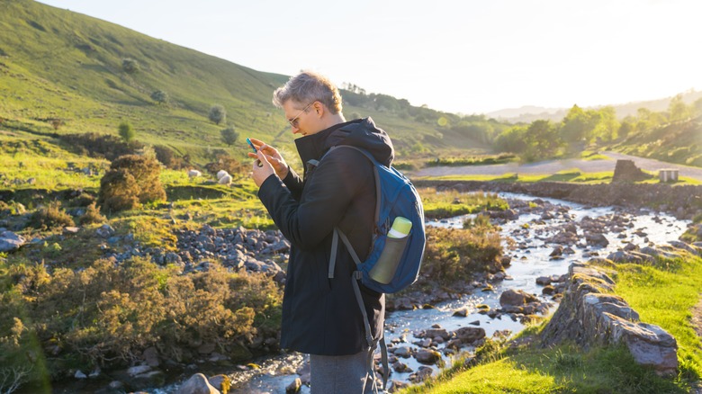 man using phone during hike