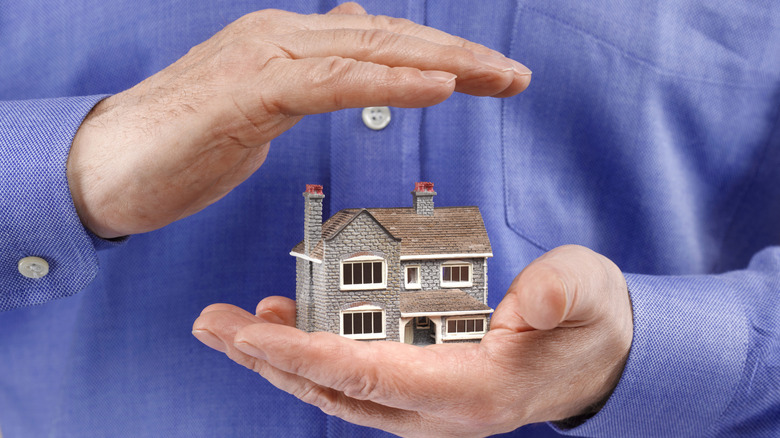 Man holding a model home securely in his hands