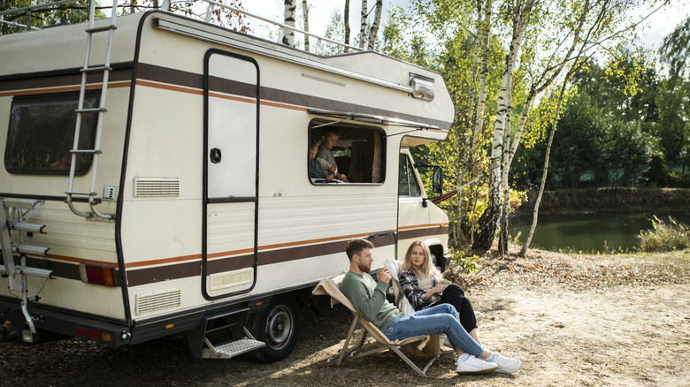 A family sitting inside and outside of an RV