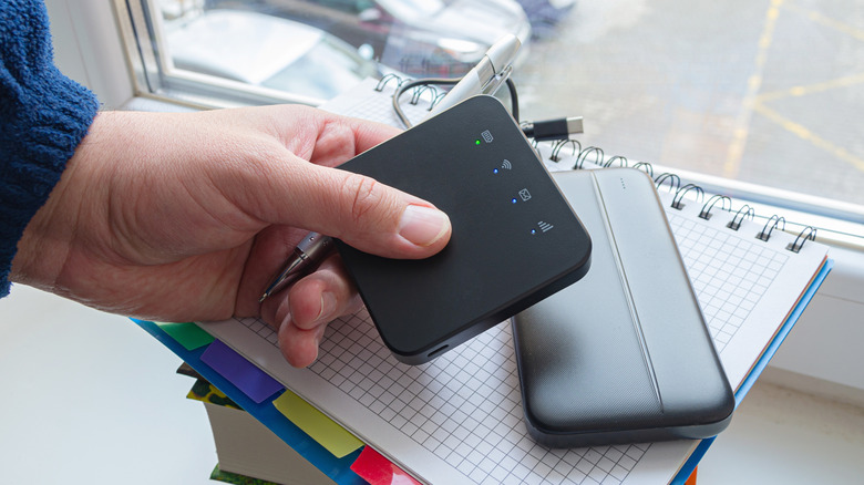 Person holding a mobile hotspot router.