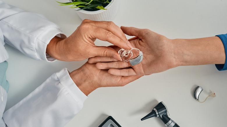 doctor giving hearing aid to someone