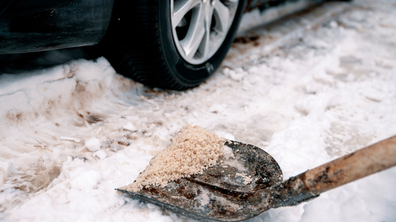 Shovel of salt and grit on snowy surface