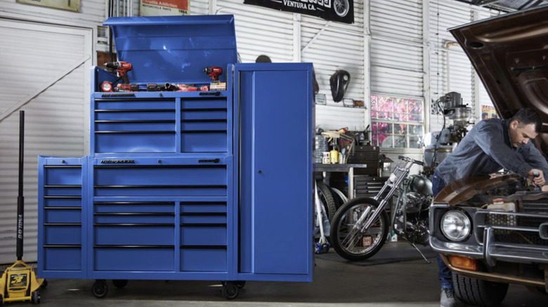 Man working on car next to blue toolbox