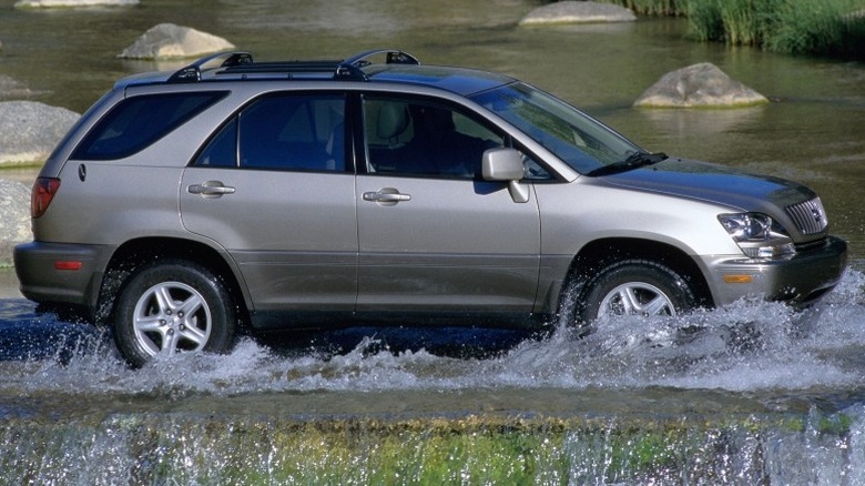 1999 Lexus RX 300 driving through a shallow river with rocks in the background