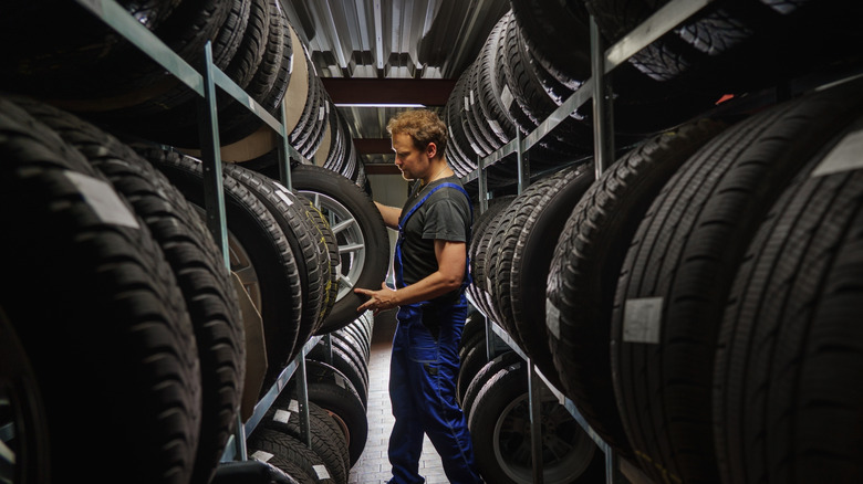 A worker grabs a tire from a large supply displayed on two large shelves