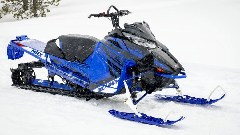 Side view of 2024 royal blue Mountain Max snowmobile parked on snow