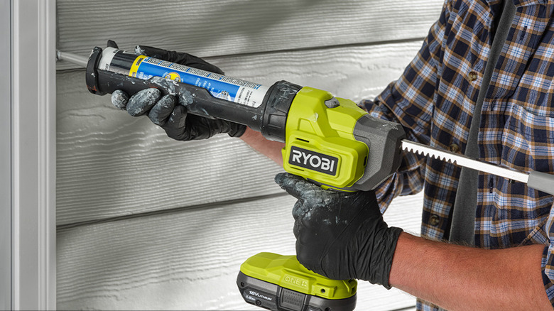 person using ryobi caulk gun