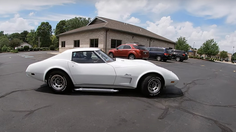 White 1976 Corvette in parking lot with newer cars and building in background