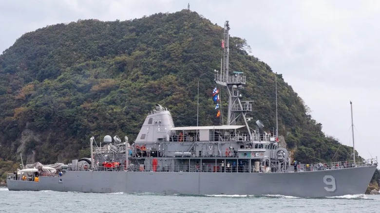 An Avenger-class ship sailing past a small island.