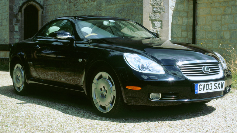 A black Lexus SC430 is parked outside.