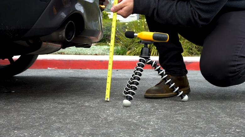 A person measures a car's volume of exhaust