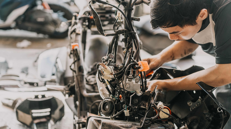 Motorcycle mechanic repairing bike at garage