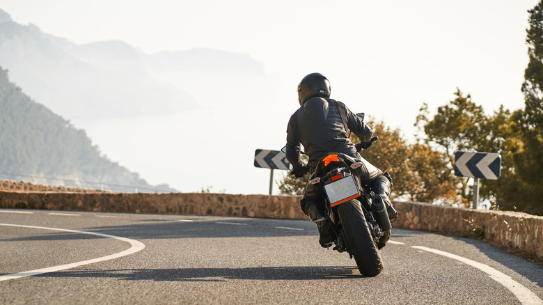 Back shot of man riding sport motorbike on a curved road