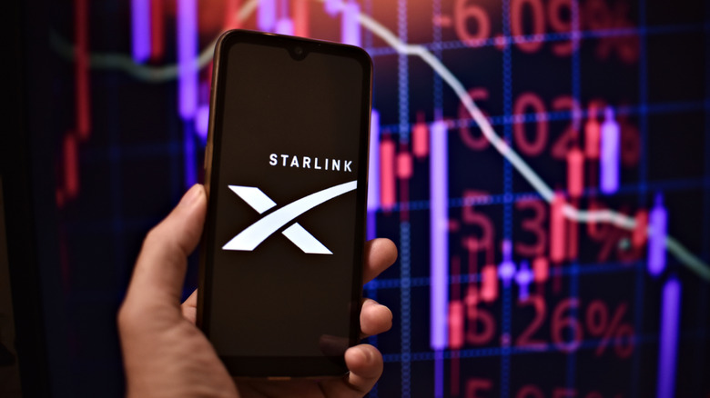 Person holding phone with Starlink logo and numbers chart in background