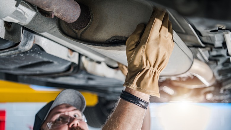 man touching catalytic converter