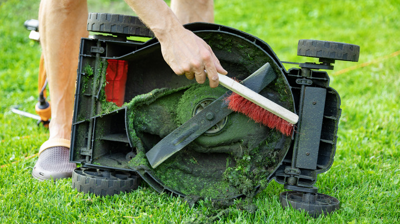 Man cleaning lawn mower blade