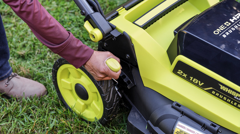 Person adjusts their Ryobi lawn mower