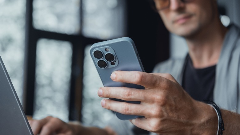 man using iPhone and MacBook