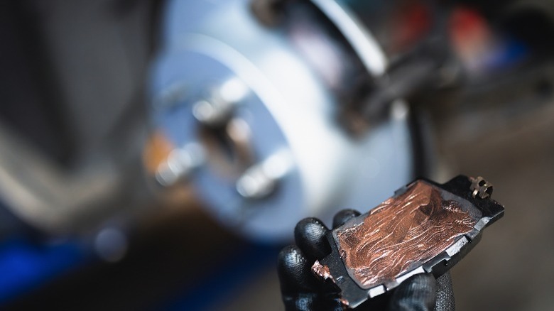 Mechanic applying grease on the backplate of a brake pad