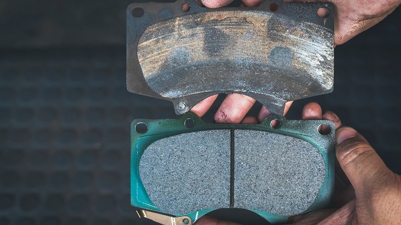 Worn brake pad and new brake pad held side-by-side