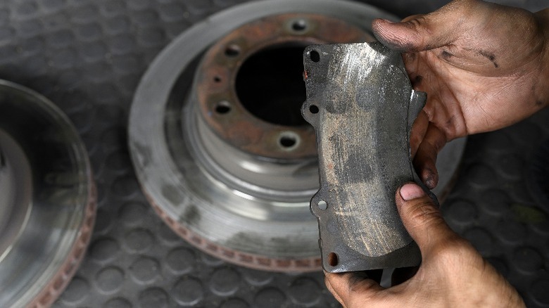 Worn and old brake pad next to disassembled rotor