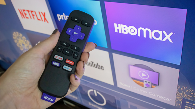 Roku remote held in front of a TV