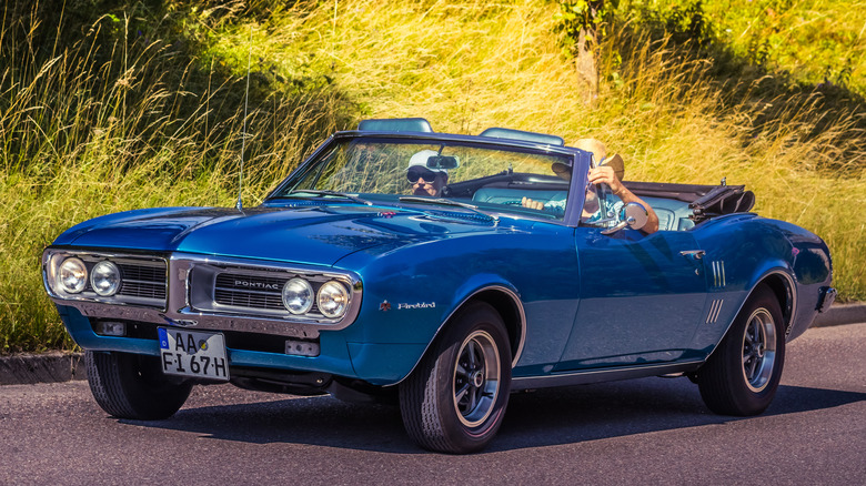 Blue Pontiac Firebird convertible riding on country road