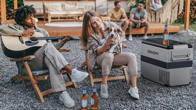 man playing guitar while woman holds dog