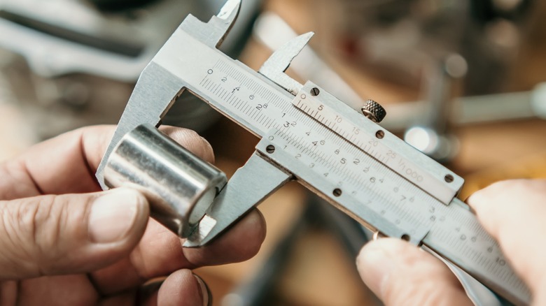 Measuring the length of a bushing with vernier calipers.